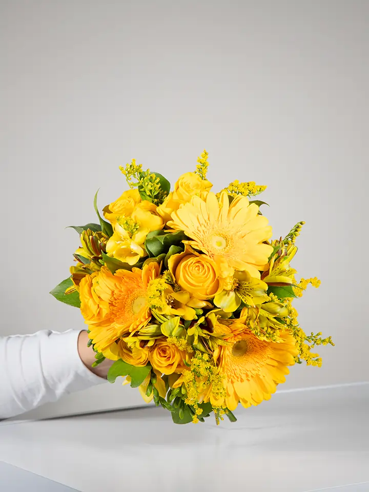 Bouquet giallo di rose e gerbere in mano